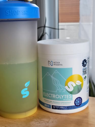 Client avec le pot d'Électrolytes Nova Pharma et un shaker de la boisson préparée.