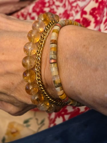 Close-up of a customer's 'Life Is Tough But So Are You Bracelet' with flat, earthy beads, worn in a stack on their wrist.