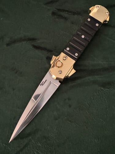 Reviewer's custom knife with a polished blade and gold handle, showing the finish from the sanding belts.