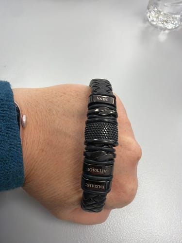 Customer's hand wearing the black braided bracelet with several personalized name pendants.