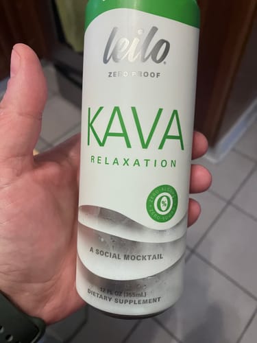 Customer holding a white and green can of Leilo Kava Relaxation tonic, a zero-proof social mocktail.