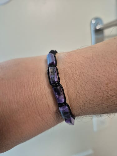 Photo d'un client portant le Bracelet Homme Charoïte avec des pierres violettes rectangulaires au poignet.