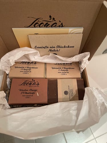 Kunde zeigt die Kokosmilch & Ringelblume Seifen in einer geöffneten Versandbox von Loona's.