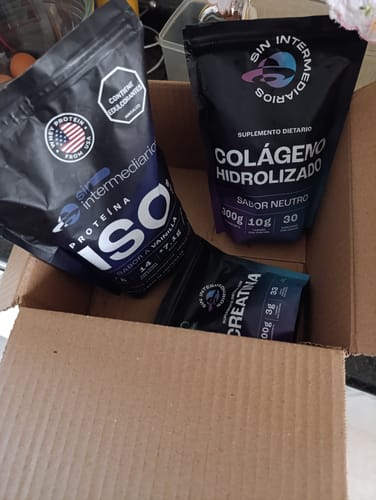 Un cliente muestra la Proteína Aislada (ISO) en su empaque negro, dentro de una caja de cartón abierta junto a otros productos.