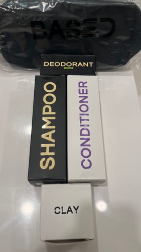 Customer's Shower Duo shampoo and conditioner boxes displayed with clay, deodorant, and a branded bag.