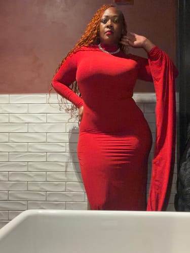 Customer wearing the red Naked Draped Sleeve Maxi Dress, showing the mock neckline and dramatic draped sleeve.
