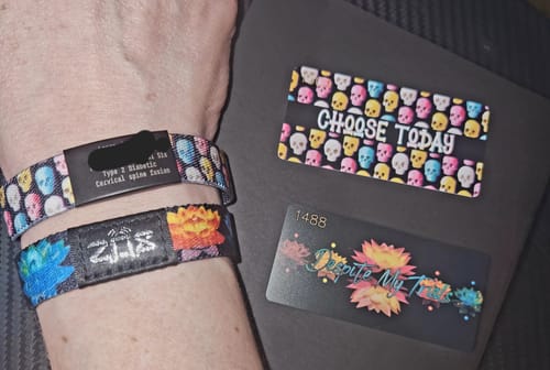 Reviewer shows their wrist wearing the colorful skull-patterned Choose Today Bracelet with a medic alert tag attached.