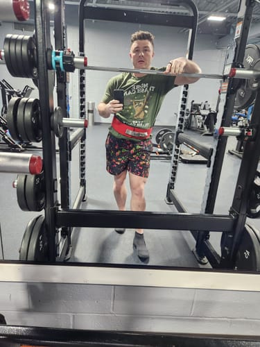 Reviewer at a squat rack in a gym, wearing the colorful Supernova V1 Lined Training Shorts.