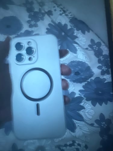 Reviewer holding a light-colored MagCase Metal, showing the camera cutout and MagSafe ring.