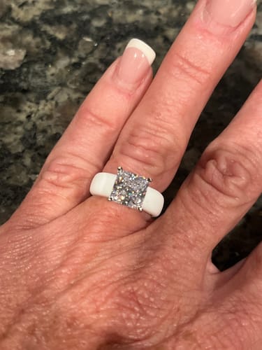 Customer's hand wearing the Silicone Ring, showing the white band and large princess-cut CZ stone.