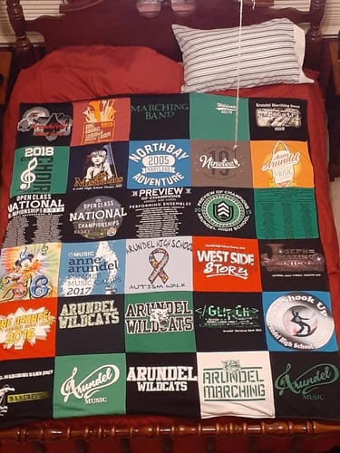Customer's colorful Project Repat T-Shirt Quilt, made from many event shirts, laid flat on a bed.