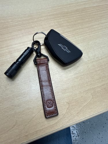Reviewer's brown leather Effortless Keychain attached to a key ring with a car key fob and a small flashlight.