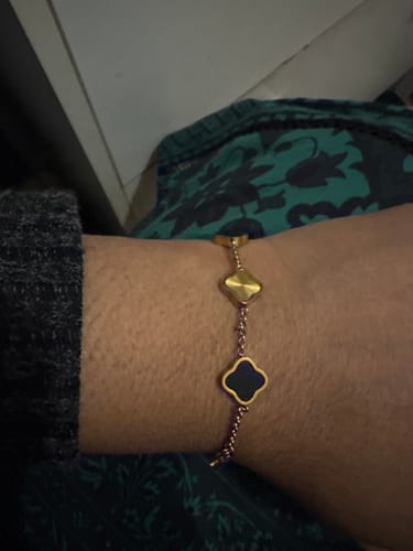 Customer shows off their gold-toned bracelet with clover-shaped charms on their wrist.