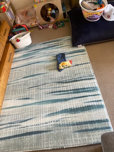 Reviewer's Mellow Mat in the Coastal Drift print laid out on the floor of a living space, surrounded by toys.