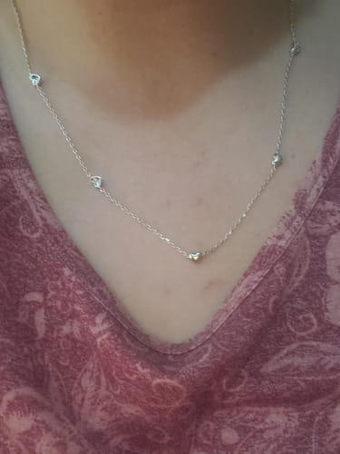 Reviewer wearing the Jane Heart Station Necklace, showing the delicate chain with small, spaced-out heart details.