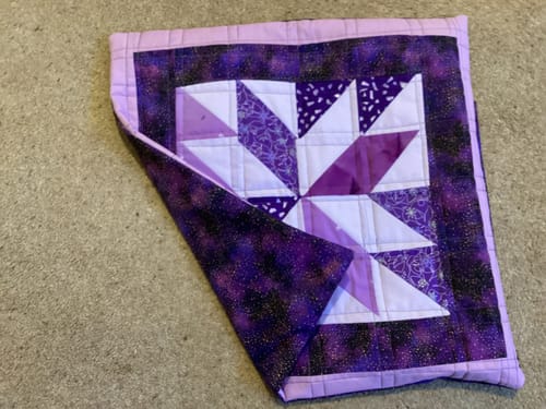 Customer's quilted cushion using the purple Galaxy cotton print as the border and backing for a star pattern.