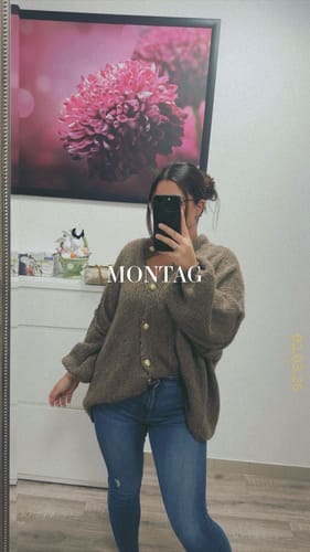 Kundin macht ein Spiegelselfie in einer Strickjacke und Jeans; der Rock „Summer“ ist nicht zu sehen.