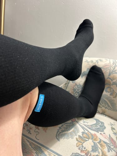 A customer's legs resting on a couch, showing the fit of the black Performance Eucalyptus Compression Socks.