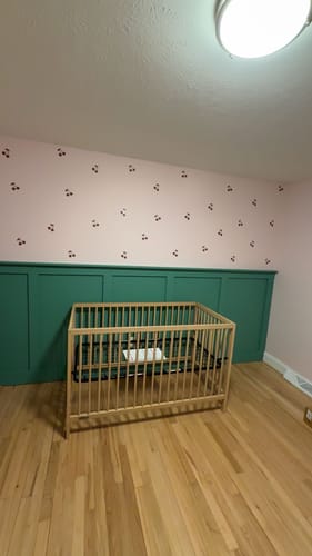 Customer's clear stickers with a cherry design applied to a pink nursery wall above a crib.
