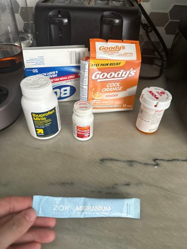 Customer displays a sachet of Migranium in front of other over-the-counter pain medications.