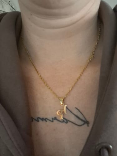 Ein Rezensent trägt die goldfarbene Halskette mit verschlungenen Initialen.