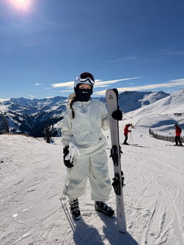 Reviewer wearing baggy snow pants and full ski gear on a sunny, snowy mountain.