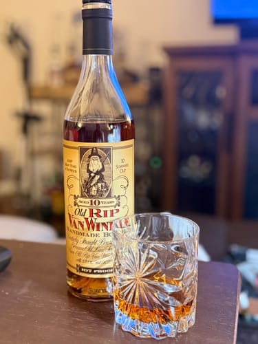 Customer's bottle of Old Rip Van Winkle 10 Year bourbon with a cut glass containing a pour of bourbon.