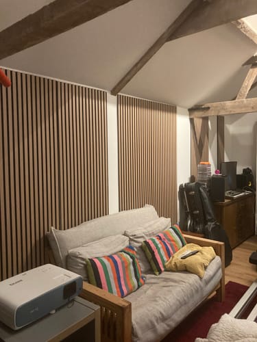 Reviewer's living room with Premium Acoustic Slatted Wall Panels installed on the wall behind a sofa.