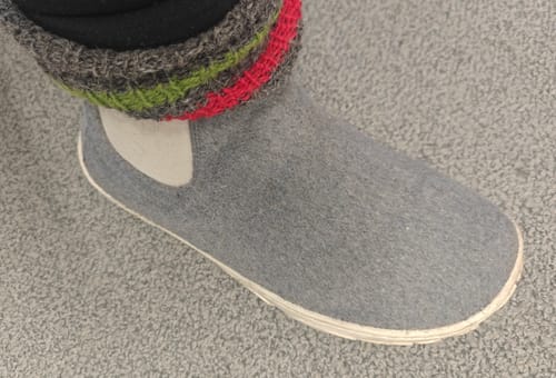 Asiakkaan jalassa harmaa Vaistoa Sulo -huopanilkkuri värikkään villasukan kanssa.
