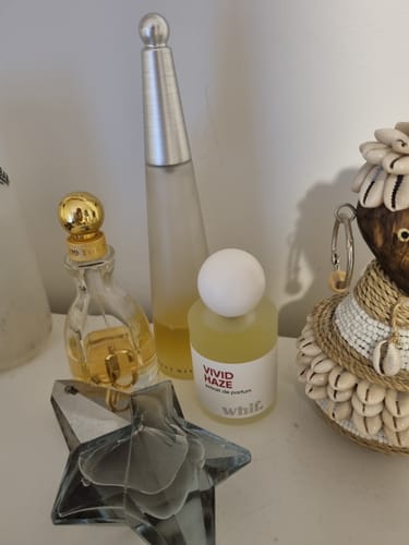 Reviewer's Vivid Haze perfume bottle shown with their collection of other assorted fragrances on a counter.