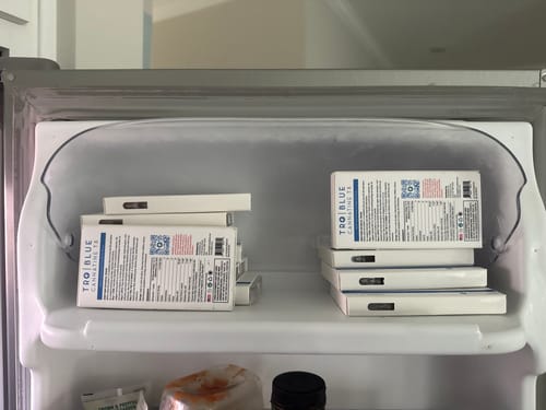 Customer's stock of Blue Cannatine™ boxes organized in two stacks on a refrigerator door shelf.