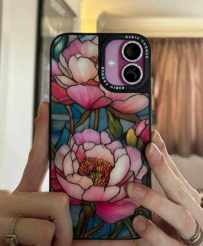 Reviewer holding their iPhone, showing the Peony Reverie Case with its detailed, stained-glass floral design and camera bumper.