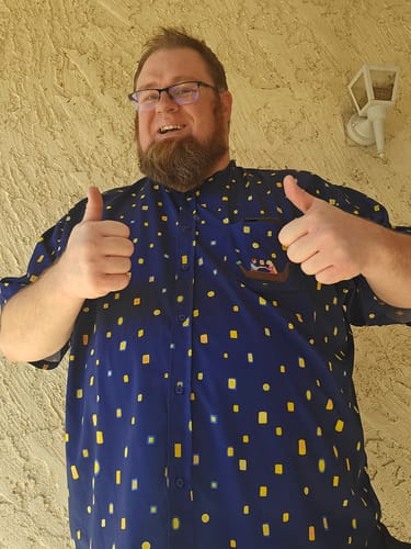 Reviewer gives two thumbs up while wearing the navy Disney's Tangled "Lanterns" short sleeve shirt.