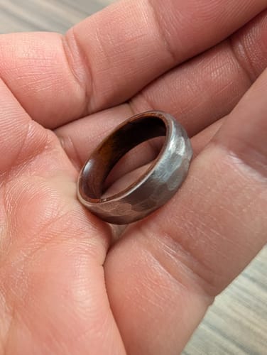 Customer holding their warrantied replacement ring, showing its hammered metal finish and wood interior.
