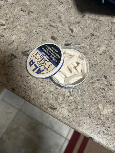 Customer's open can of ALP Chilled Mint Nicotine Pouches sitting on a stone countertop.