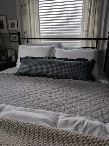 Customer's long navy gingham pillow with a ruffle edge, centered on a neatly made bed.