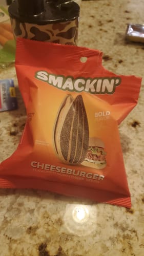 Customer's red single bag of Cheeseburger flavored sunflower seeds torn open on a countertop.