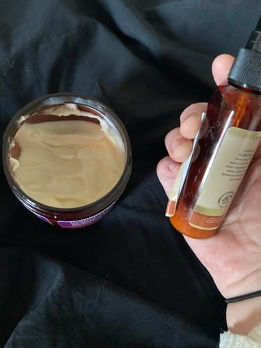 Customer holds a partially used Refresher Spray next to an open jar of the Gourmet Whipped Shea Body Butter.