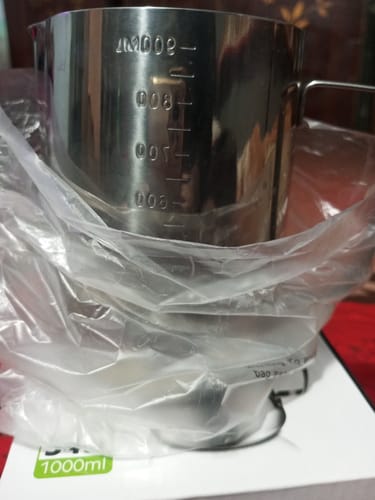Customer's stainless steel 1000ml milk frothing pitcher partially in its packaging, showing measurement markings.