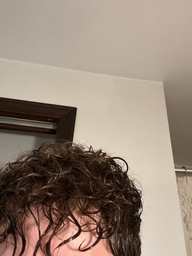 Close-up of a reviewer's wet, curly hair after applying the Curl Mousse.