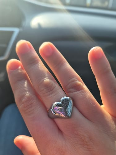 Reviewer's hand wearing the silver, heart-shaped Cosmic Heart Ring in natural light.