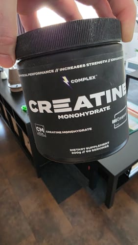 Customer holding a black tub of Complex Creatine Monohydrate in their hand.