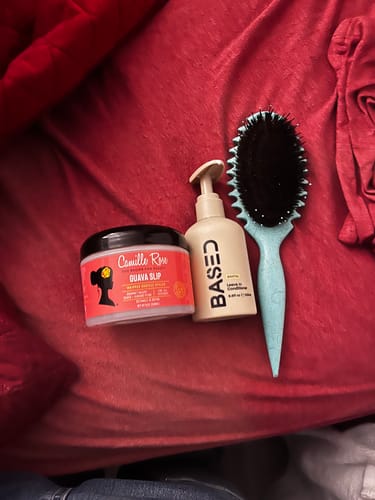 Customer's Curly Duo hair products, a leave-in and a styling jar, shown with a hairbrush.