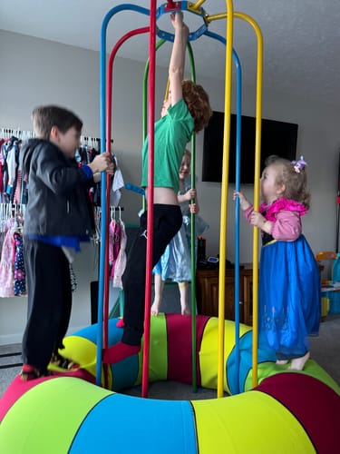 Customer's colorful Jungle Jumparoo Tube Cover with several children playing on it indoors.
