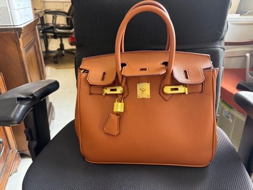 Customer's structured brown Warkin Bag with gold-tone hardware, sitting upright on a chair.