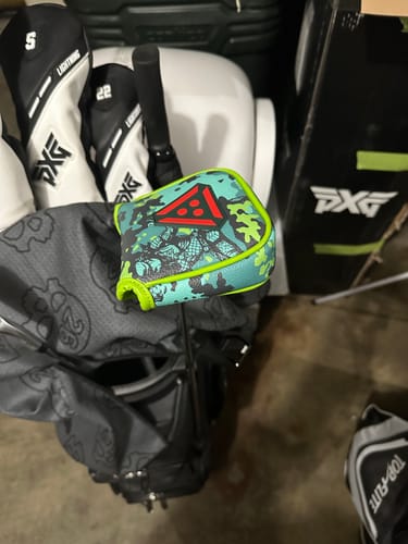 Reviewer's Predator mallet putter headcover with a jungle camo pattern and bright green trim in their golf bag.
