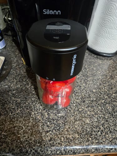 A customer's black Mason Genie Vacuum Sealer in use, sealing a large mason jar filled with tomatoes.