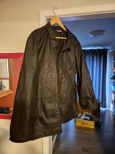 Customer's finished chore coat made from the dark brown waxed cotton fabric, hanging on a hanger.