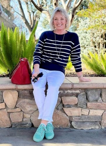 Reviewer sitting outdoors wearing her mint green Bliss Walk shoes with white pants.