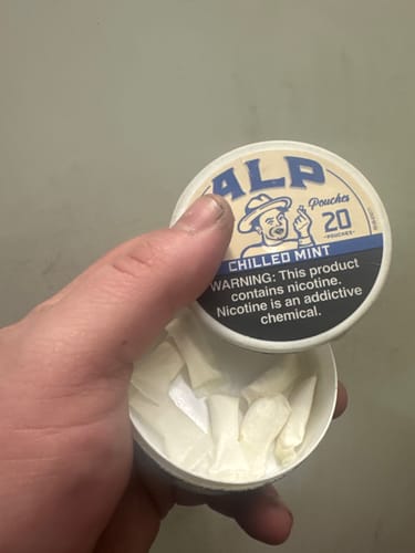 Customer holding an open tin of Chilled Mint Nicotine Pouches, showing the white pouches inside.